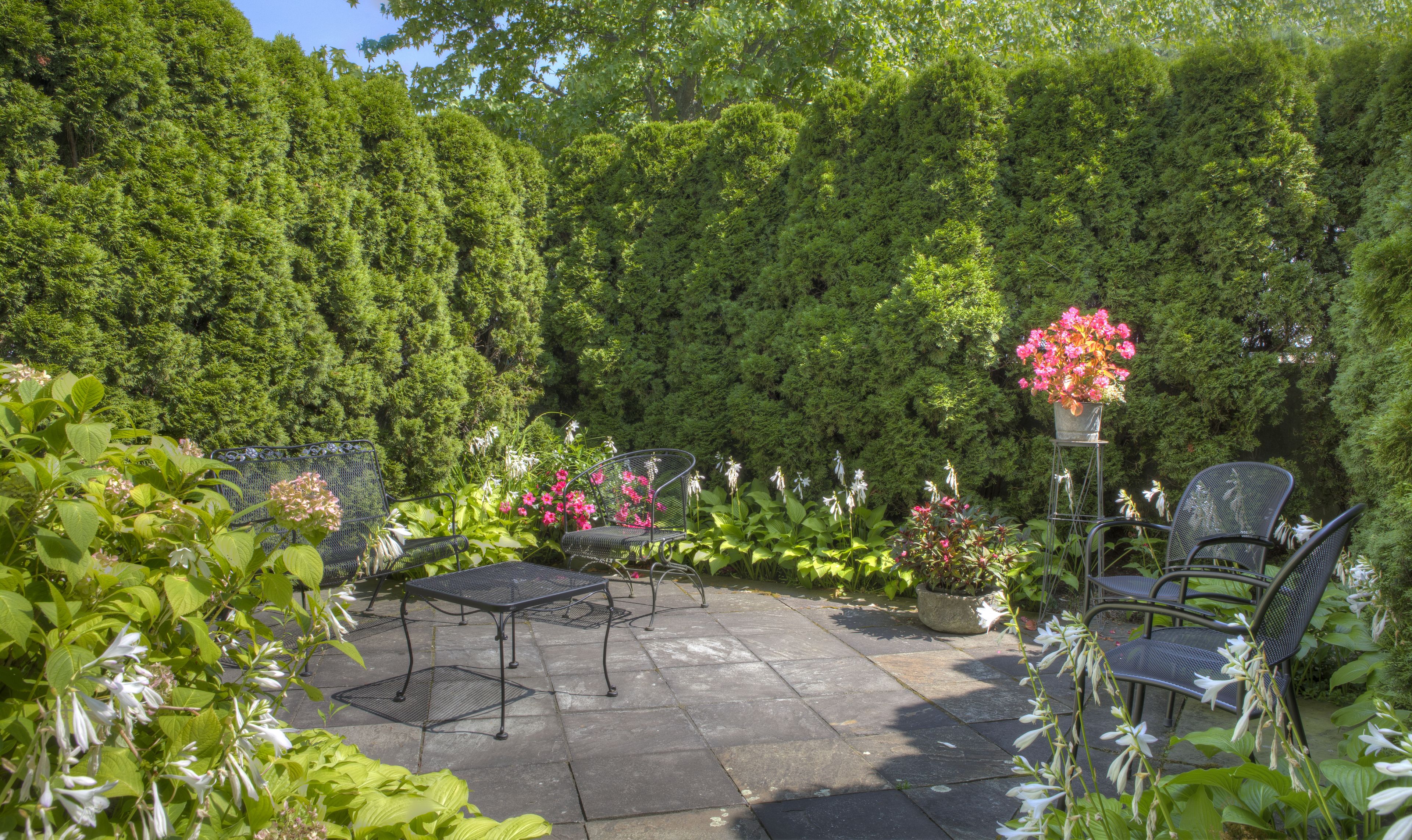 A patio with stone flooring, metal chairs, and a table.