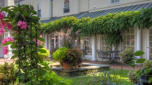 A courtyard with a stone fountain, potted plants, and a seating area with chairs. - Francis Malbone House Inn (Newport)