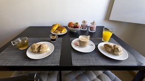 Una mesa con bollos, fruta, café y jugo para el desayuno.