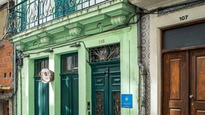 Un edificio verde con un balcón, dos puertas verdes y una puerta de madera.