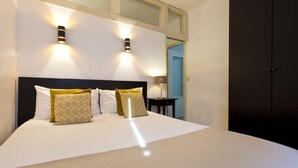 Un dormitorio moderno con una cama grande, dos lámparas de pared, una mesita de noche y un armario.