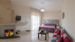 A modern hotel room with a fireplace, a bed, a sofa, and a television. - B&B La Perla dei Casali (Giffoni sei Casali)