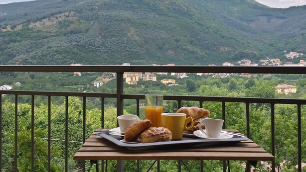 A balcony with breakfast items and a view of a mountain. - B&B La Perla dei Casali (Giffoni sei Casali)
