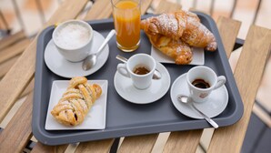 A tray with croissants, a glass of orange juice, and cups of coffee and tea on a wooden table. - B&B La Perla dei Casali (Giffoni sei Casali)