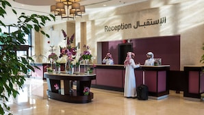 A reception area with a marble floor, a reception desk, and a chandelier. - Normas Hotel (Al Khobar)
