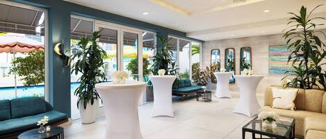 Een moderne lobby met zithoeken, grote ramen en kamerplanten.