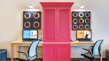 A workspace with two desks, each with a computer and a chair. There are two large red cabinets in the center.