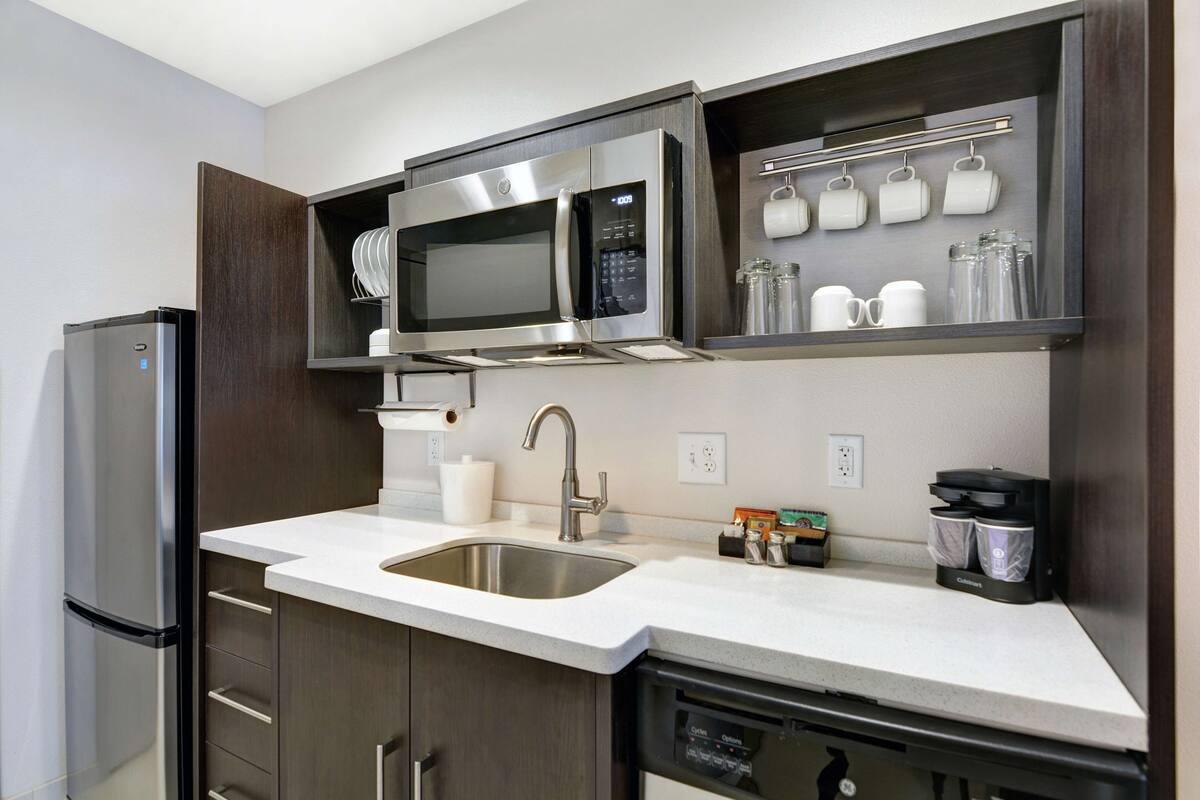 A modern kitchen with stainless steel appliances, a double sink, and a coffee maker.