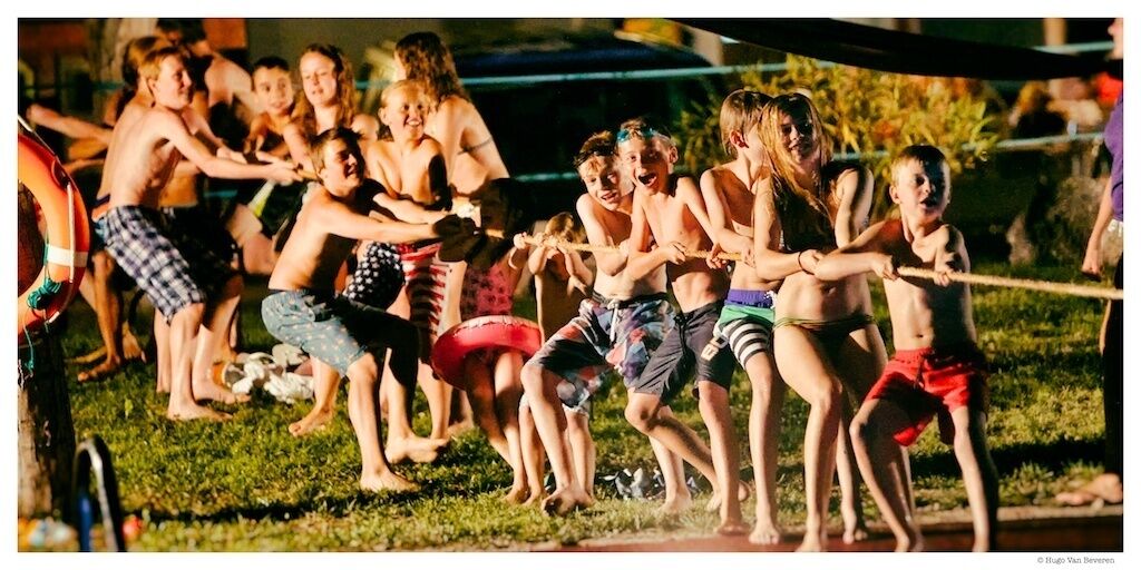 A group of people playing tug-of-war on a grassy field.