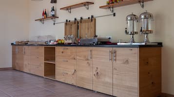 Een keuken met houten kastjes, een aanrecht en een hangplank met wijnflessen.
