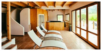 Un interior moderno con barra de madera, sillas blancas y amplios ventanales con vistas al exterior.