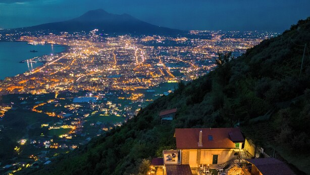 Una villa con piscina, patio y vista a la ciudad de noche.