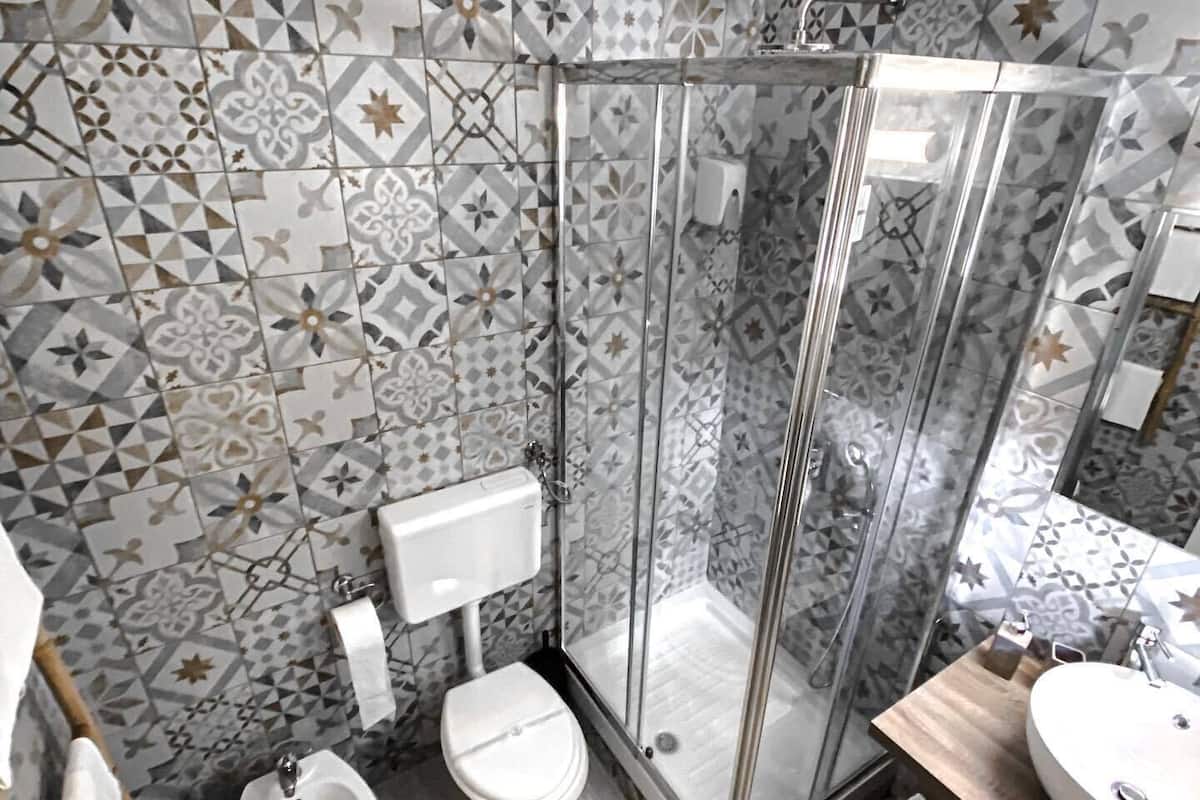 A bathroom with a shower, toilet, bidet, and sink.