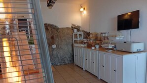 Una cocina con pared de piedra, televisor y una mesa de buffet.