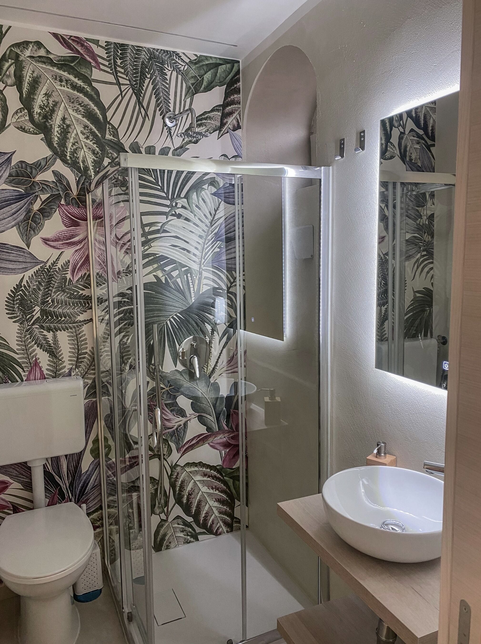 Une salle de bain avec une douche à parois de verre, un lavabo blanc et des toilettes.
