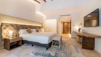 Une chambre moderne avec un grand lit, des tables de chevet, un banc, une télévision et une poutre en bois au plafond.