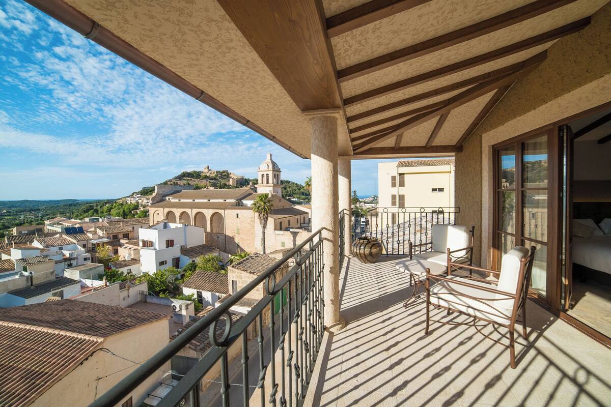 A balcony with a view of a town, including a church on a hill.