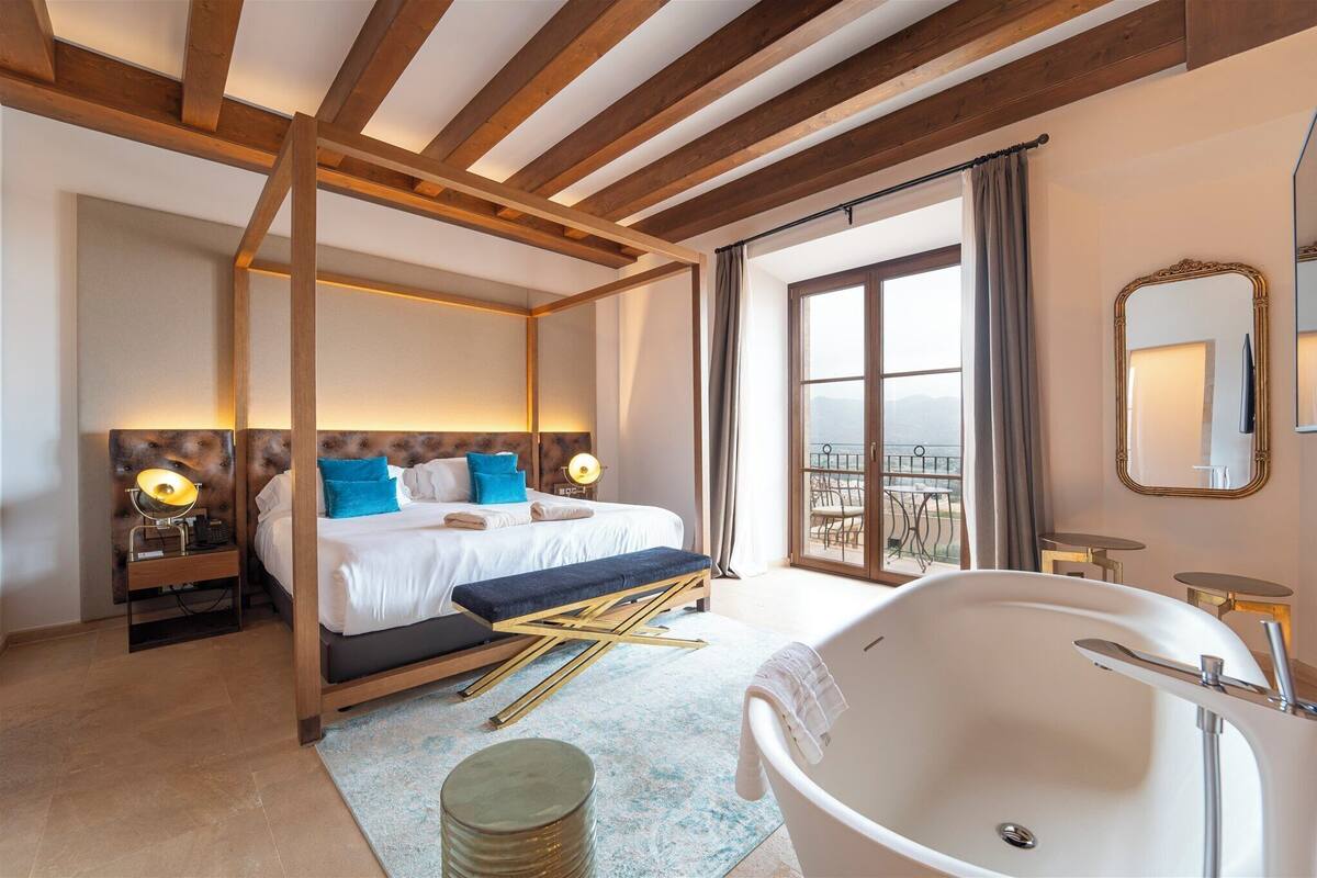 A bedroom with a large bed, a bathtub, and a balcony with a view.