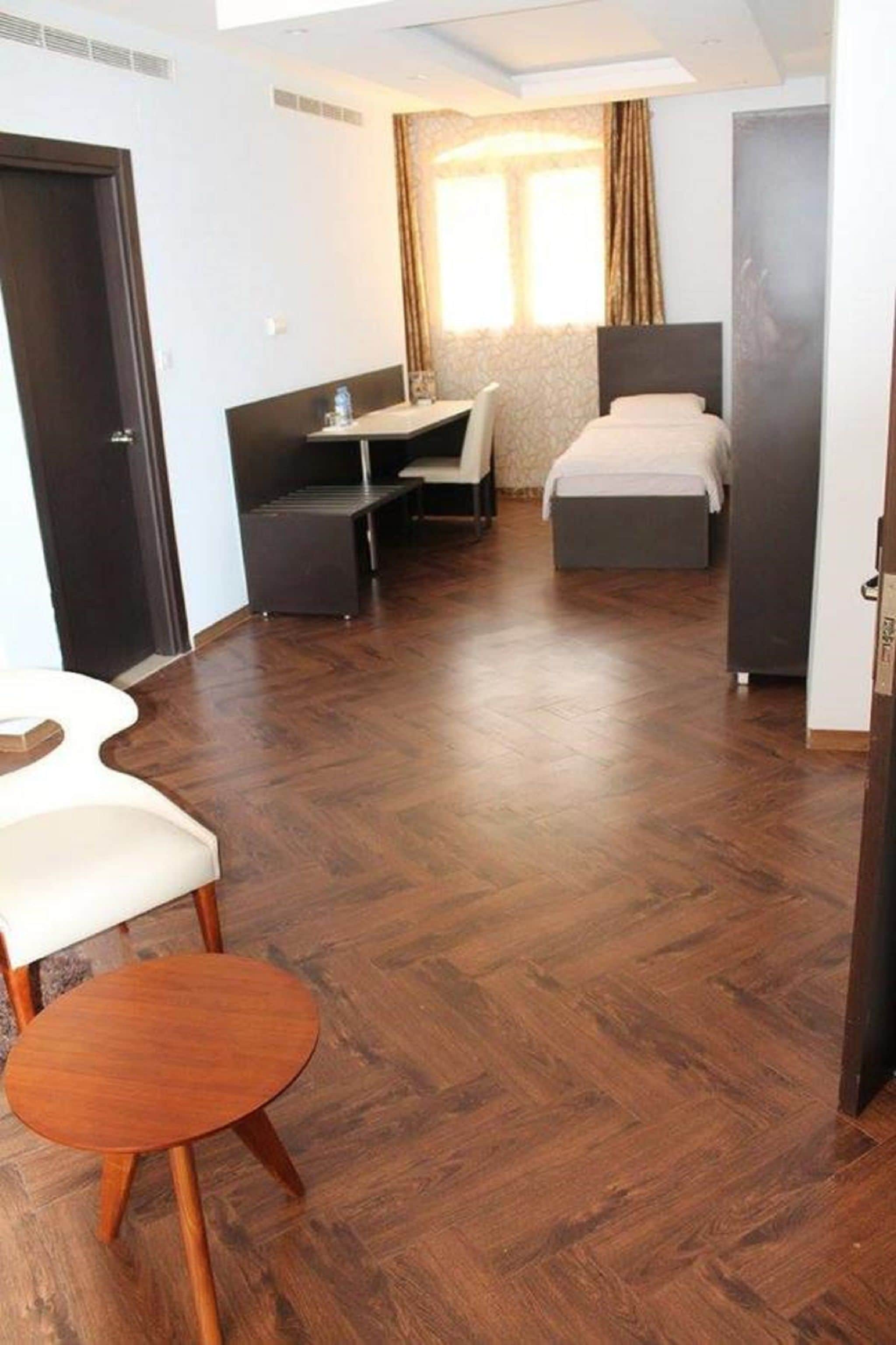 Una habitación de hotel con cama, escritorio, silla y una pequeña mesa.
