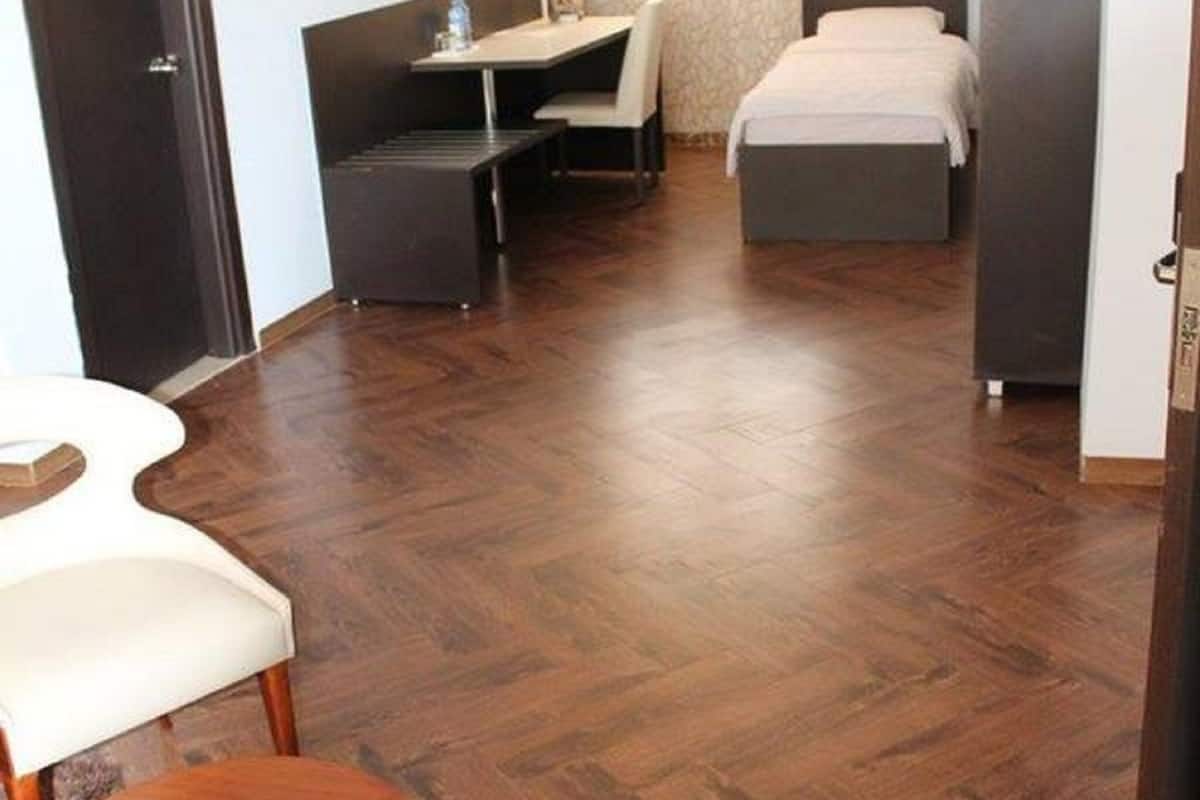 A hotel room with a bed, a desk, a chair, a small table, and a wardrobe.
