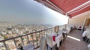 Un balcón con mesas y sillas, con vistas a un paisaje urbano.