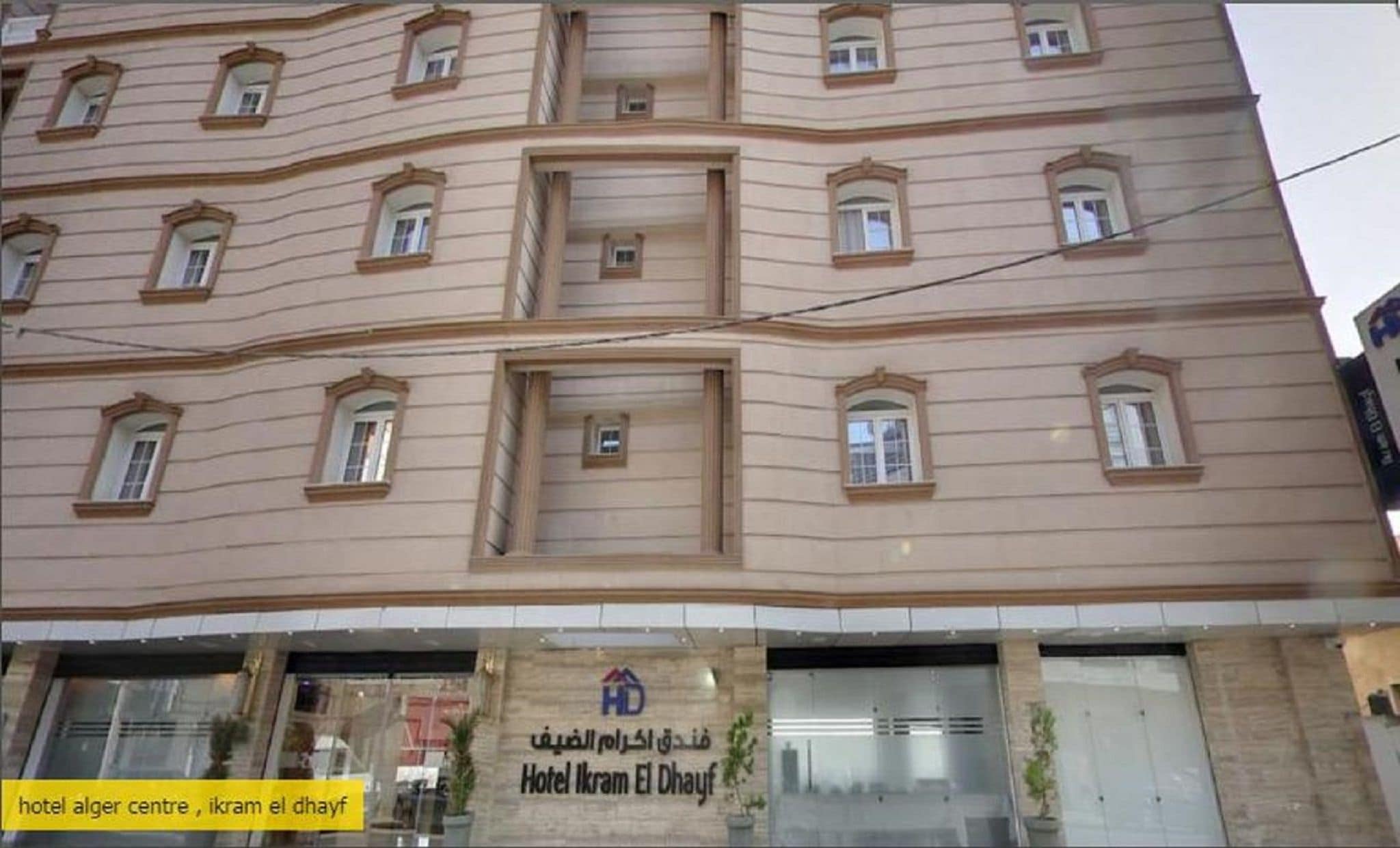 Un edificio de varios pisos con un letrero que dice 'Hotel Alger Centre, Ikram El Dhayf'.