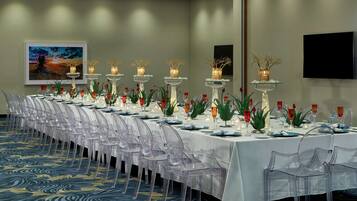 Una larga mesa de comedor dispuesta con sillas transparentes, velas y jarrones decorativos.