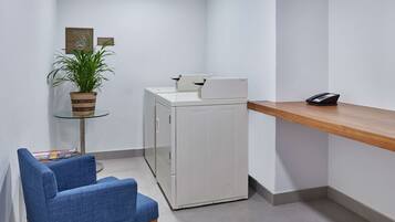 Oficina en esquina con escritorio, silla, impresora y planta en maceta.