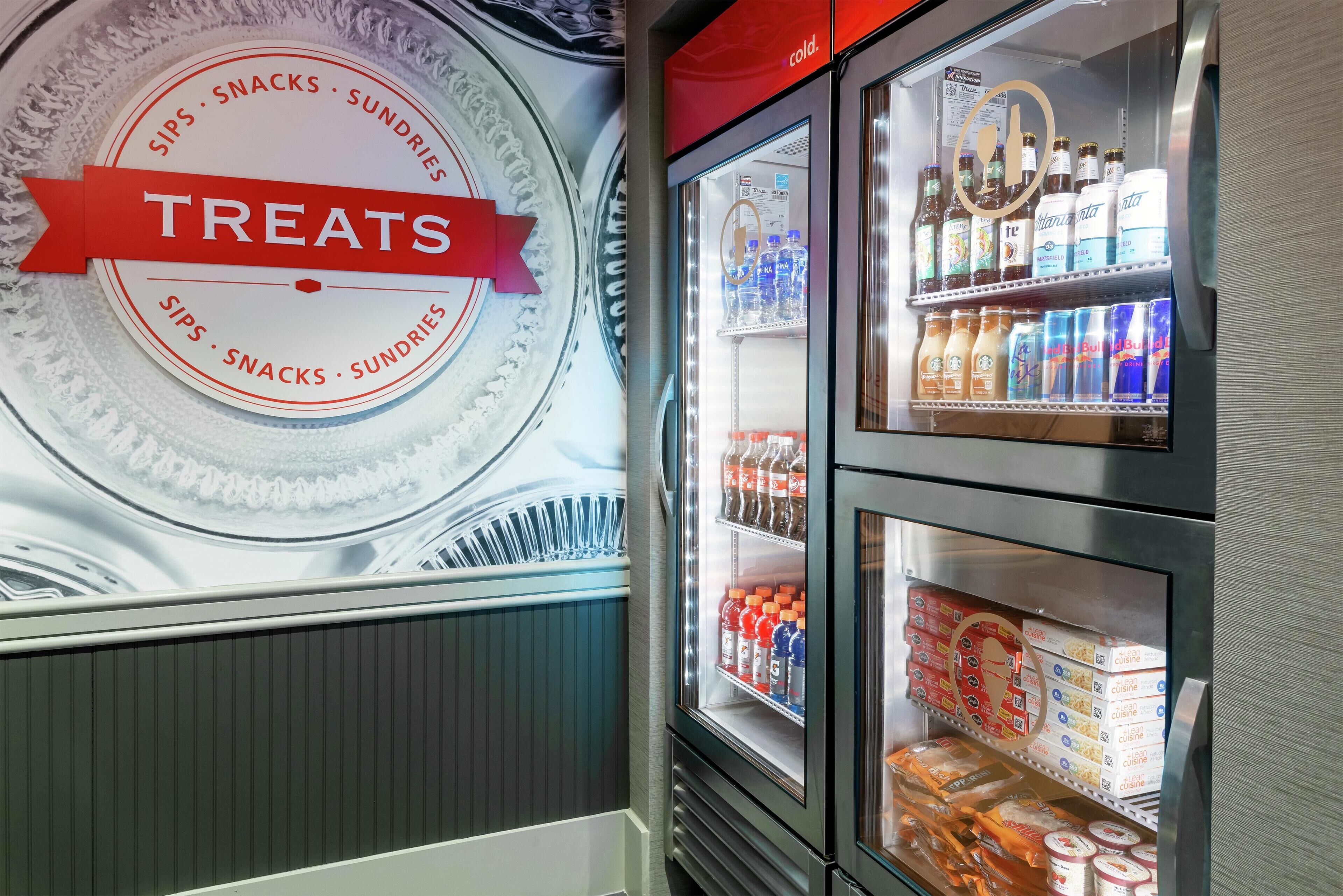 Une vitrine réfrigérée portant l’inscription « Friandises », contenant diverses boissons et produits emballés.