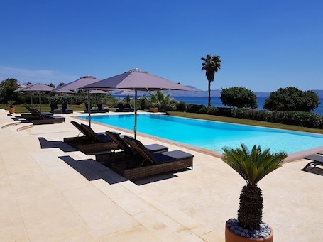 Una piscina al aire libre, sillones reclinables de piscina