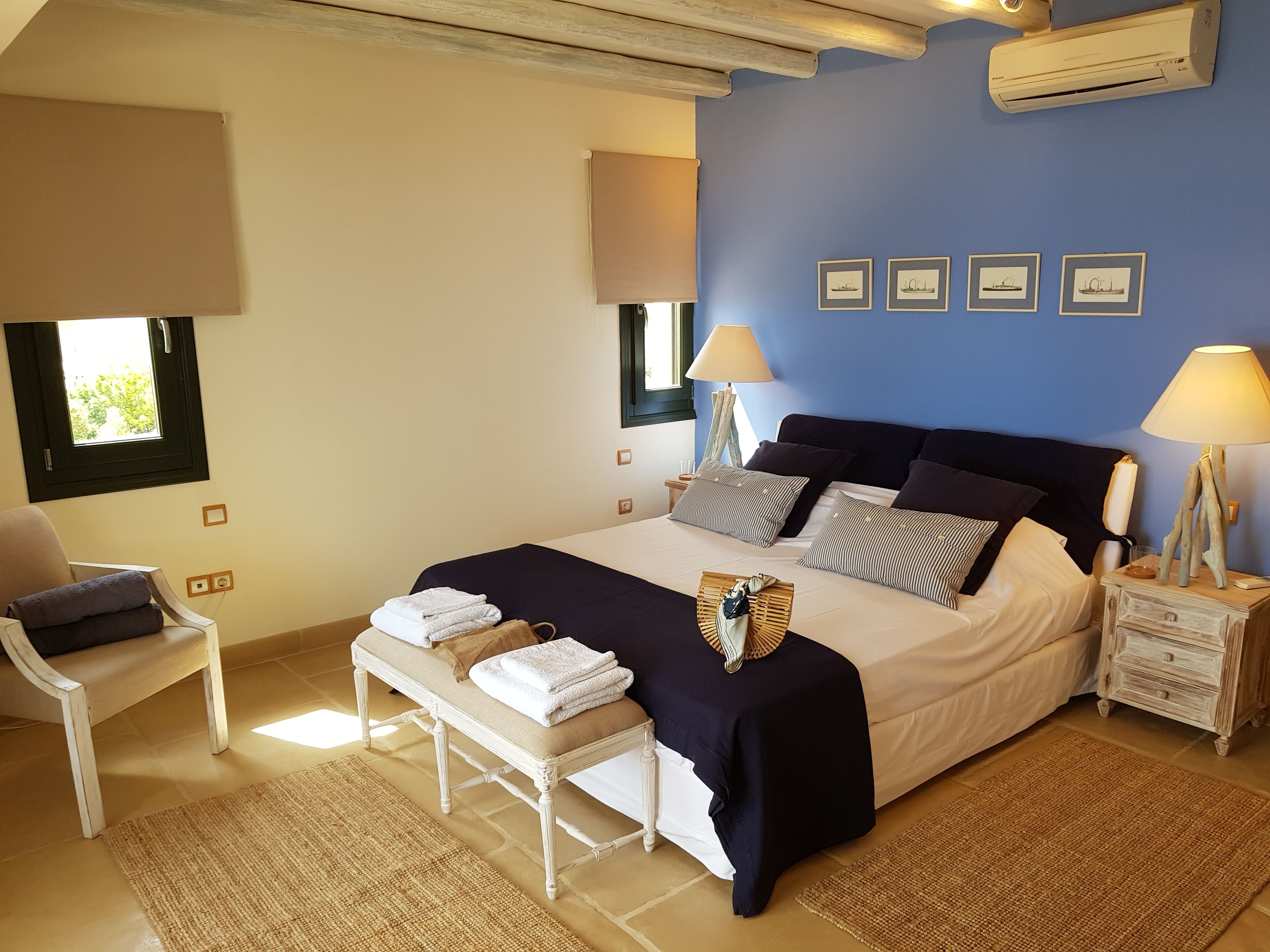Quarto com cama, mesas de cabeceira, uma cadeira e uma janela.