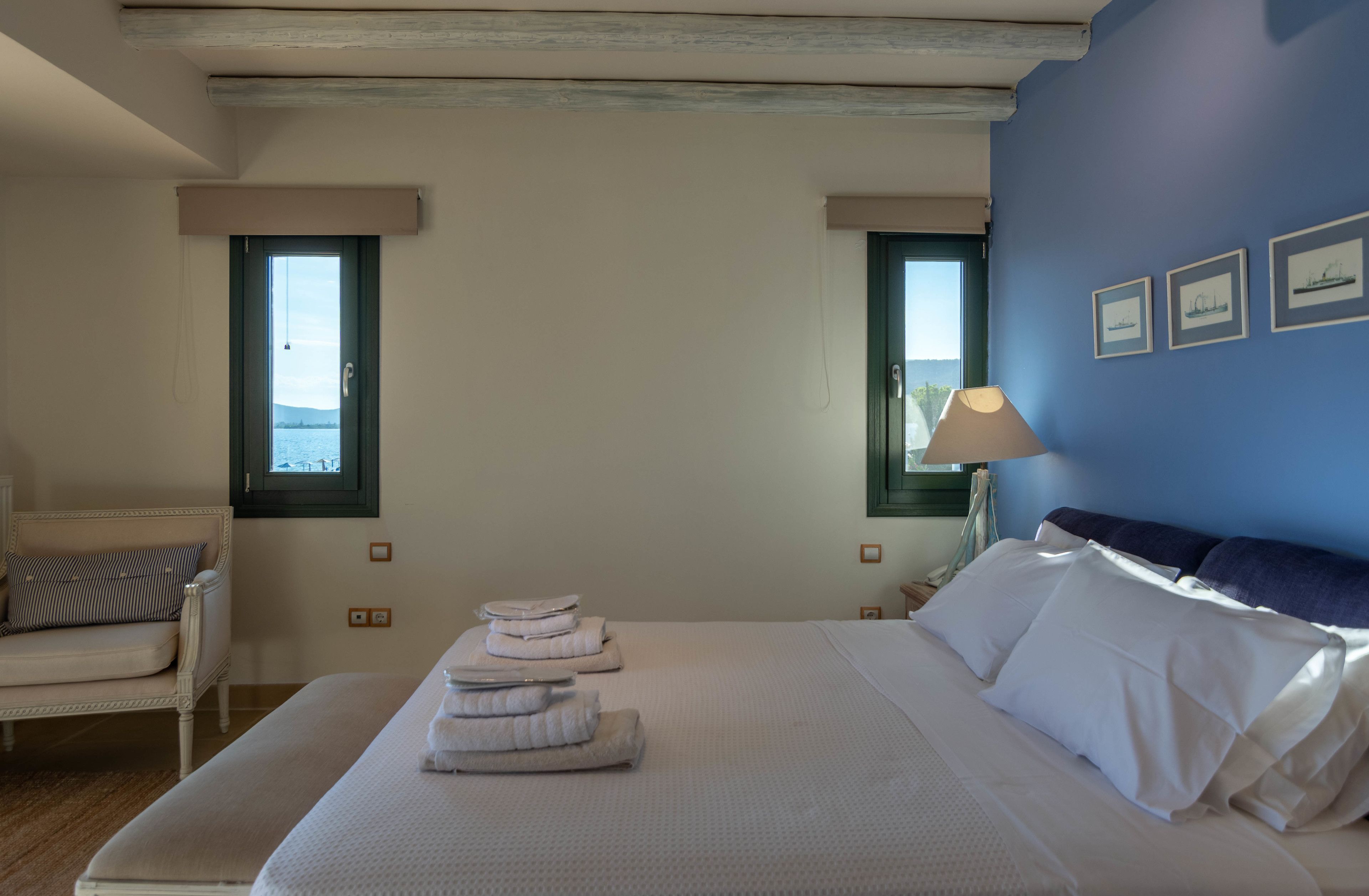 A bedroom with a bed, a chair, a nightstand, and a window with a view.