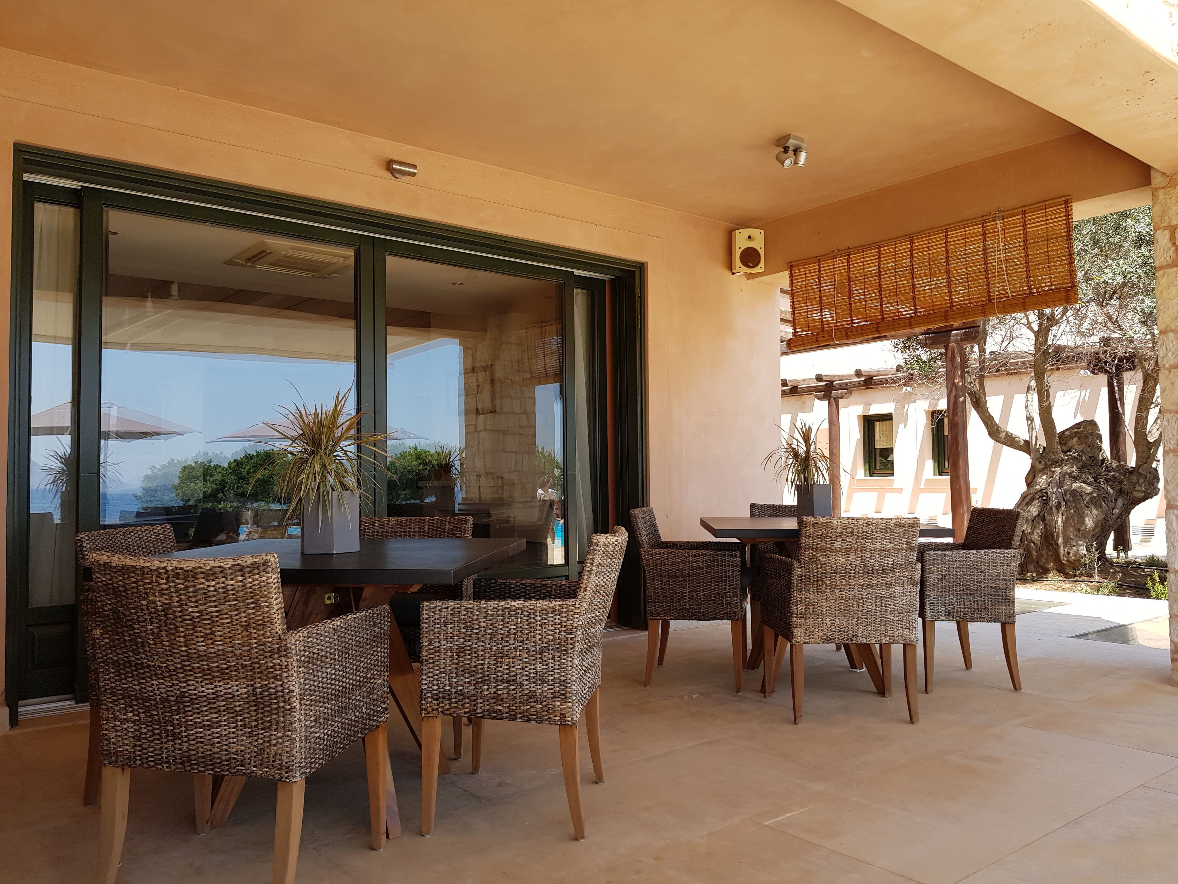 An outdoor patio with wicker furniture and a view of the sea.