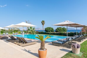 Una piscina al aire libre, sillones reclinables de piscina