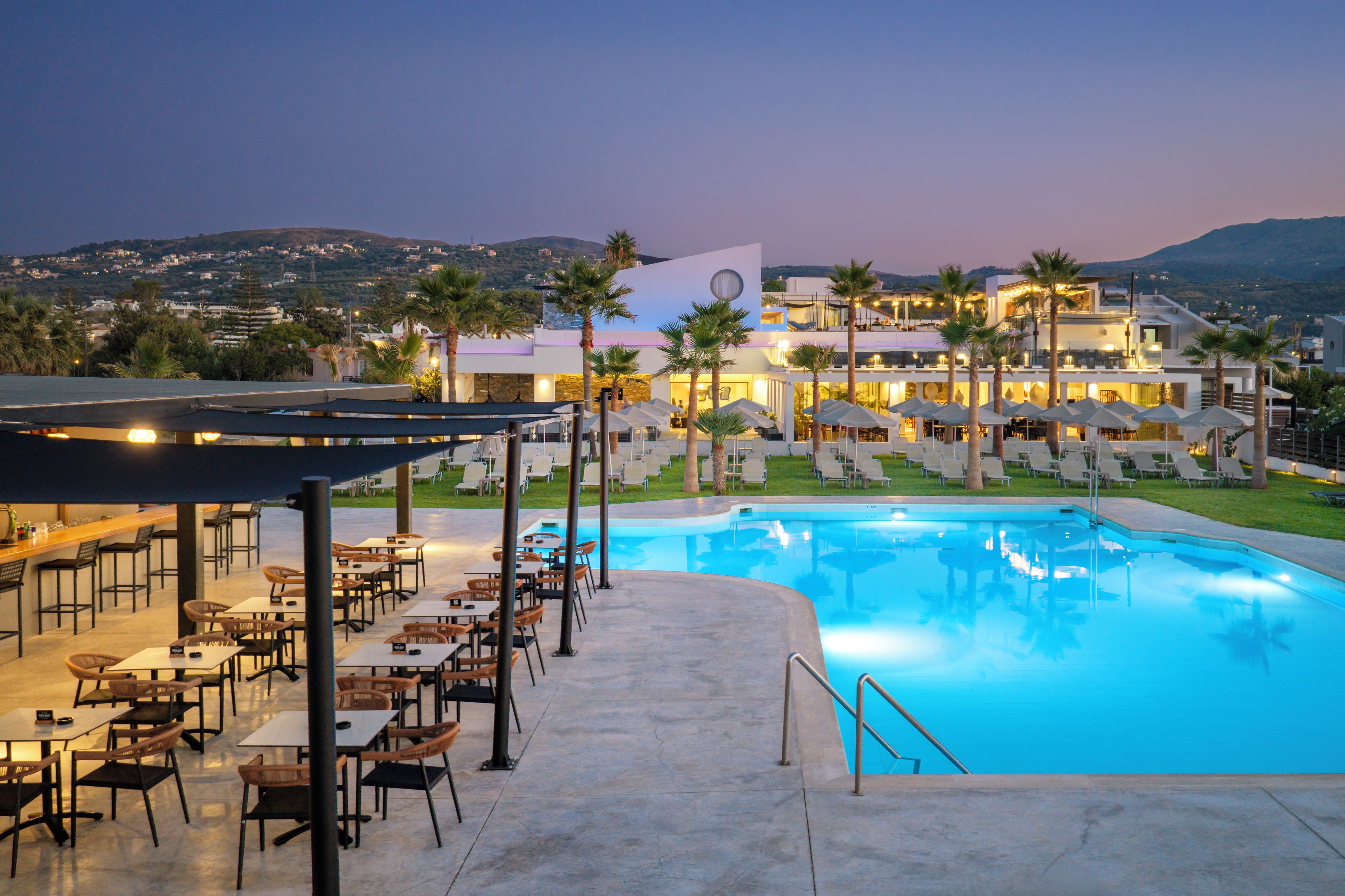 A resort pool area with outdoor seating and a view of the resort buildings.