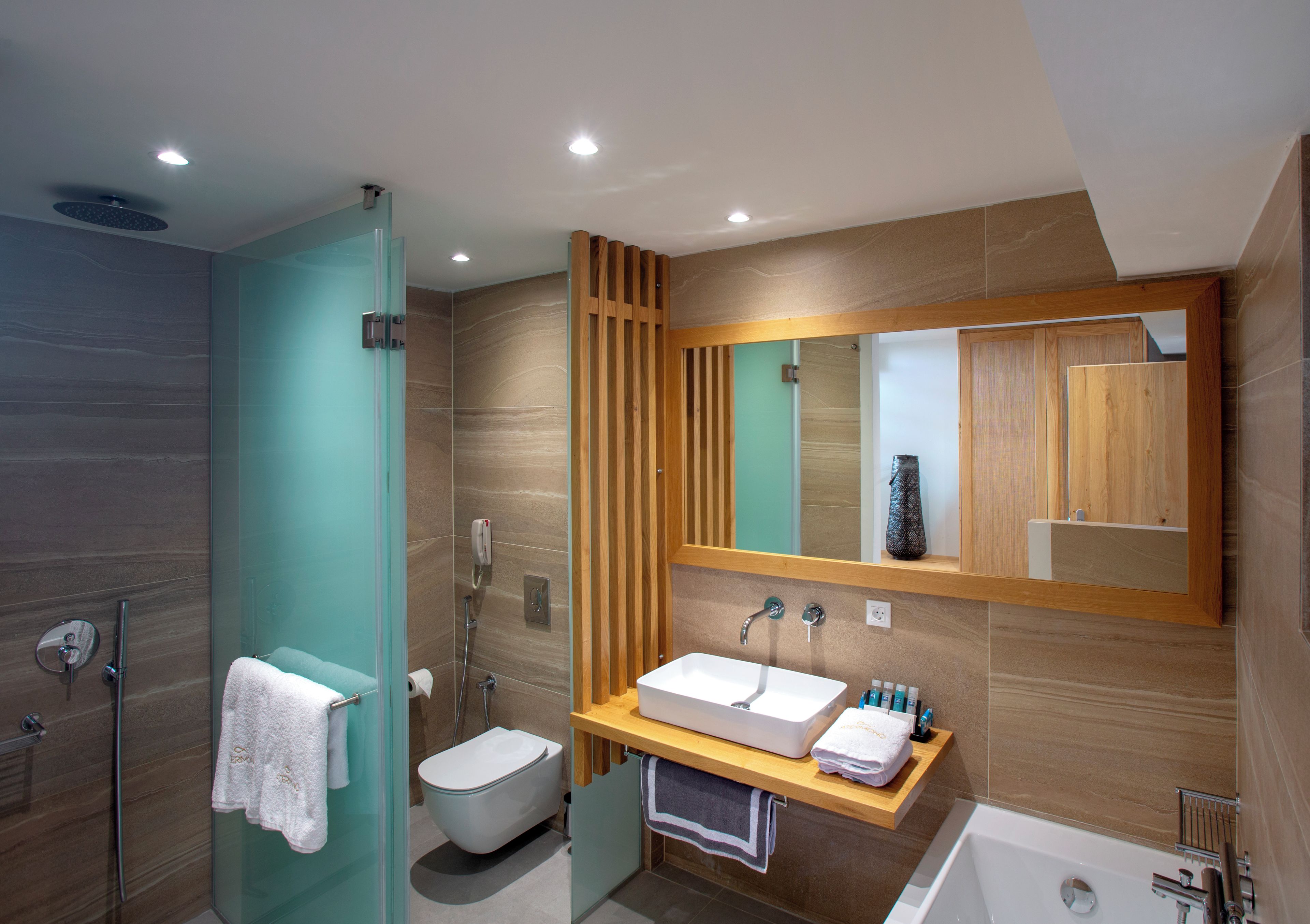 A modern bathroom with a glass shower enclosure, a white sink, and a large mirror.