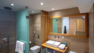 A modern bathroom with a glass shower enclosure, a white sink, and a large mirror.