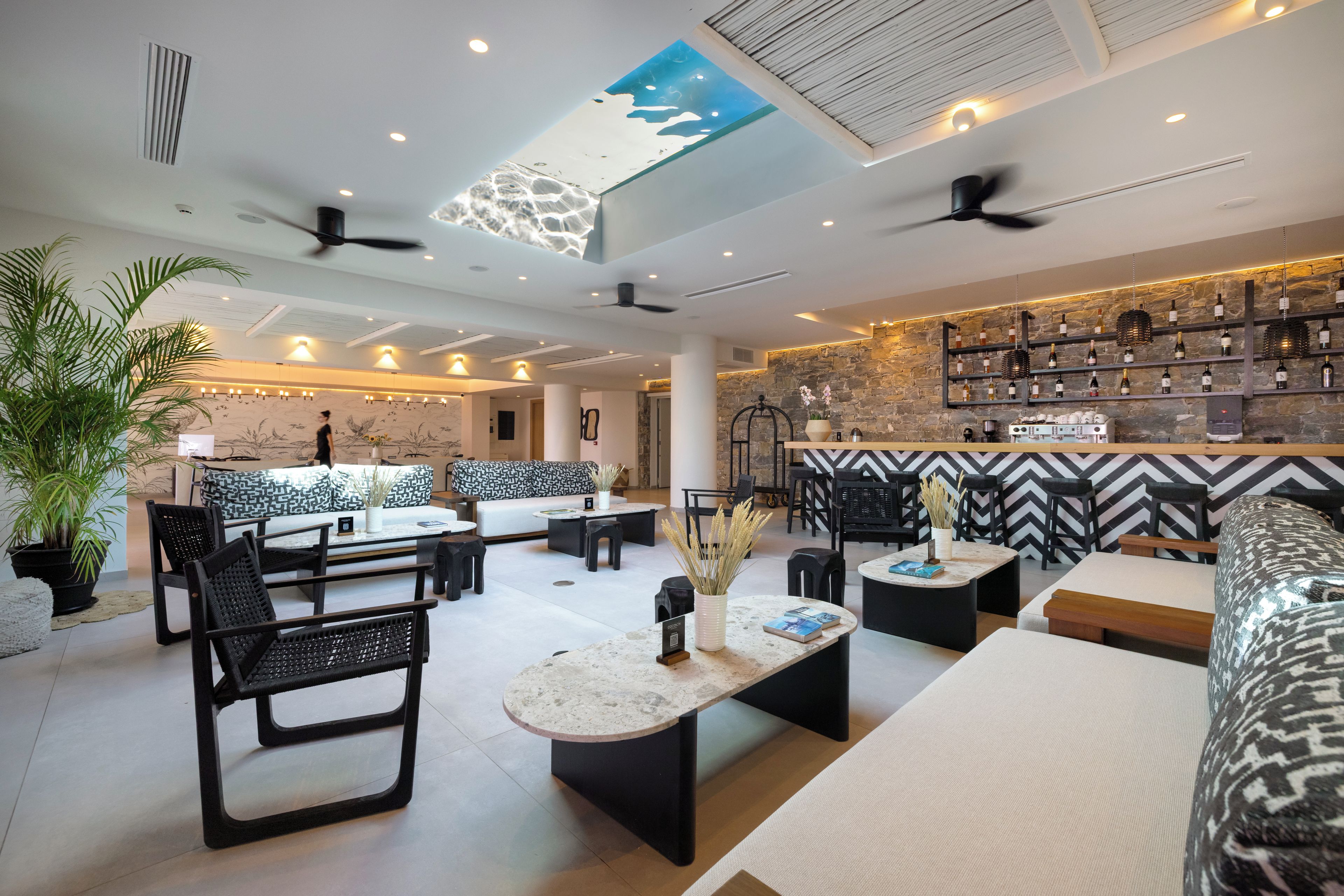 A modern lounge area with seating, a bar, and a ceiling with a skylight.