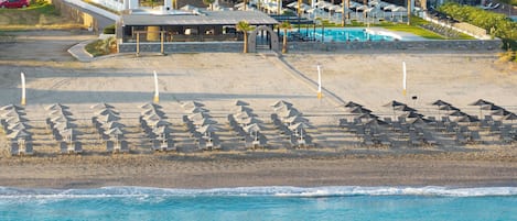 Un hotel frente a la playa con piscina, tumbonas y vistas al océano.