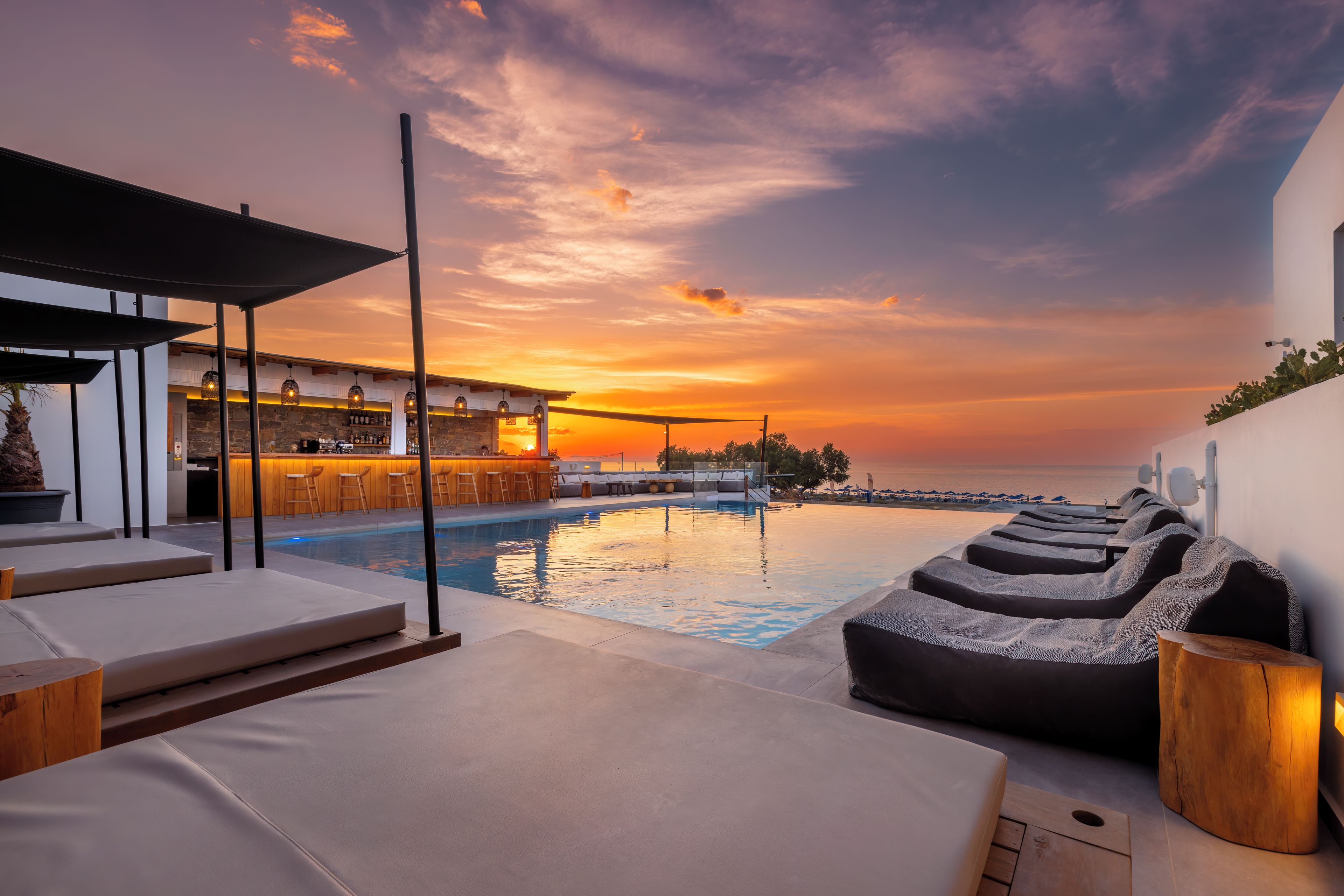 Zona junto a la piscina con sillones de descanso y un bar.