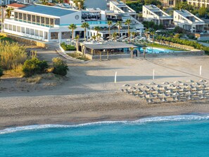 Une propriété située en bord de mer, dotée d’une piscine, de plusieurs bâtiments et d’une plage de sable.