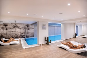 A modern spa area with two reclining massage chairs, a wall mural of palm trees, and a small indoor pool. - Atermono Boutique Resort & Spa  (Rethymno)