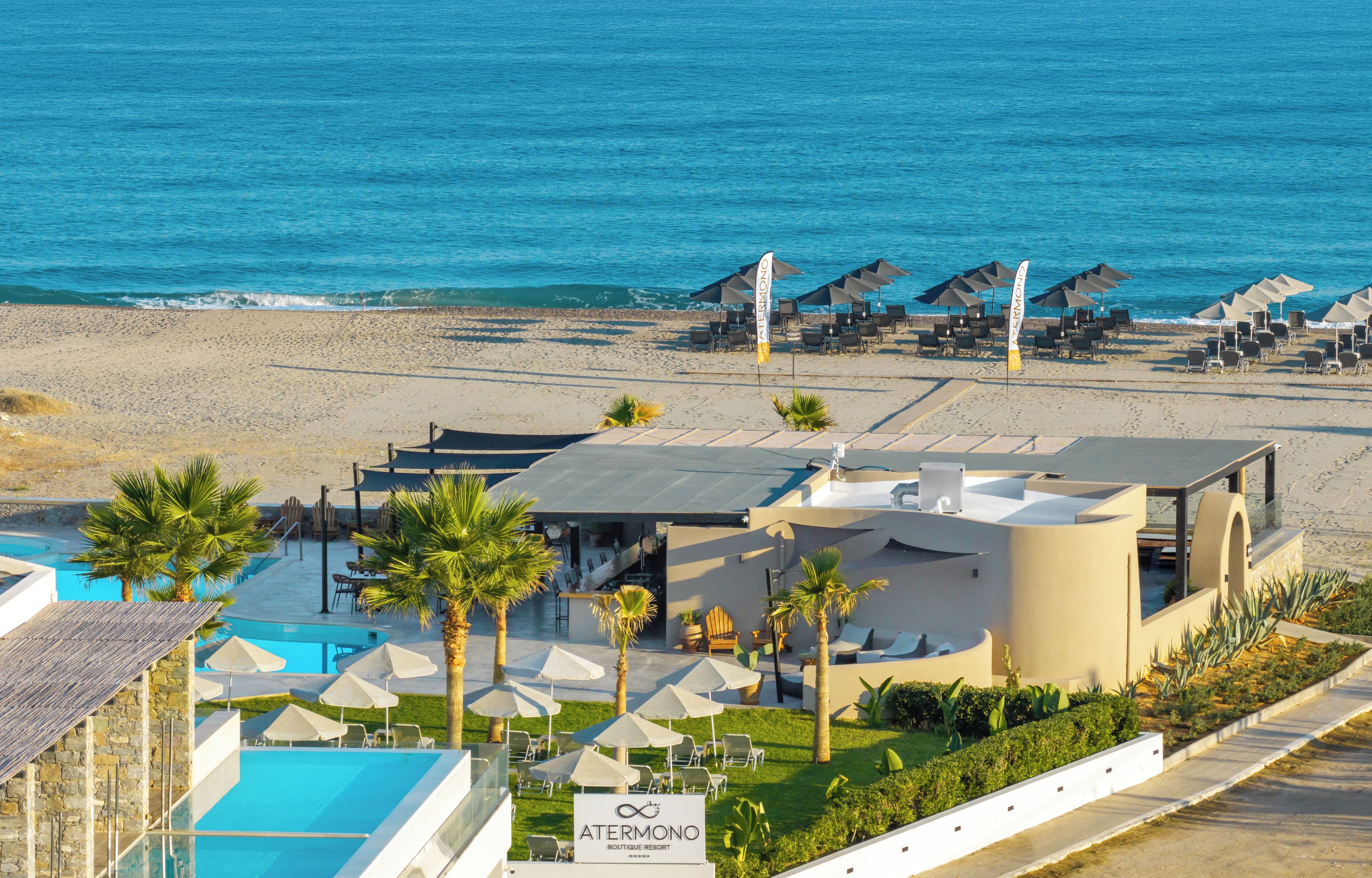 A resort with a pool, beach umbrellas, and a view of the sea.