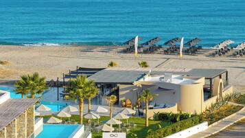 A resort with a pool, beach umbrellas, and a view of the sea.