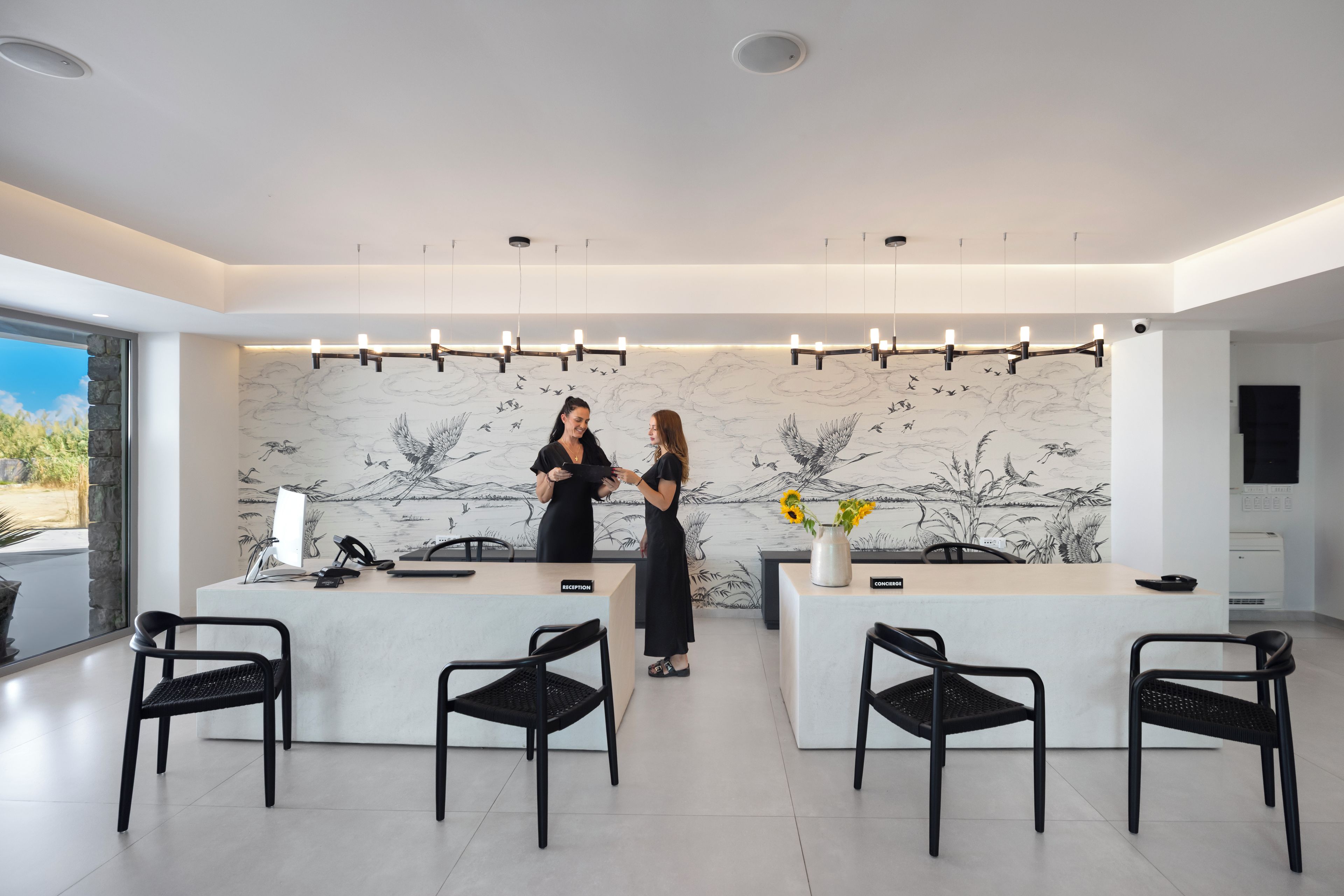 Una moderna reception con due poltrone, un'ampia finestra e un muro decorato con un murales a tema naturalistico.