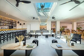 A modern interior with a bar area, seating with black and white patterned cushions, and a ceiling with a large window overlooking a pool. - Atermono Boutique Resort & Spa  (Rethymno)