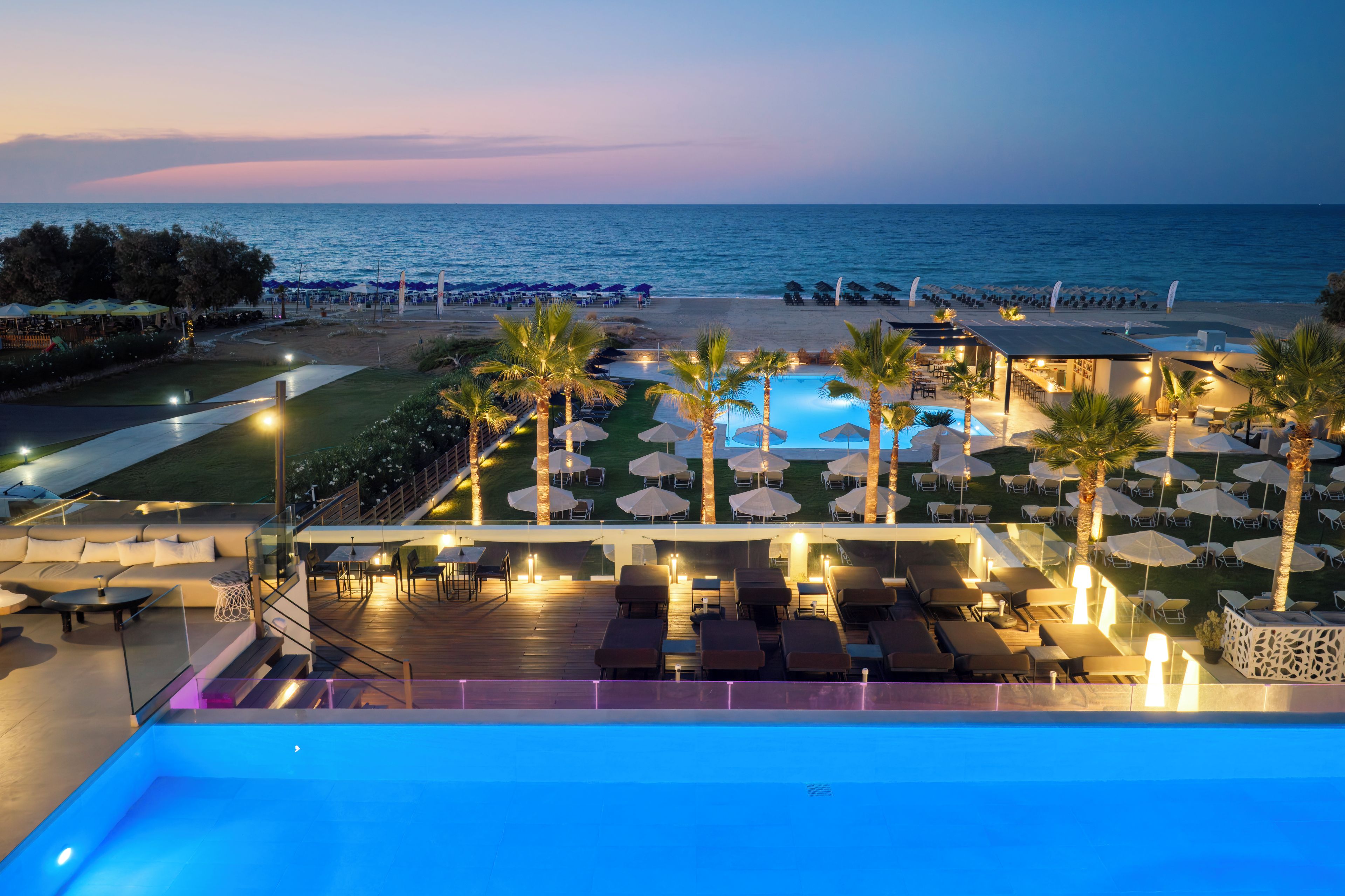 Area piscina di un resort con poltroncini, ombrelloni e vista sull'oceano.