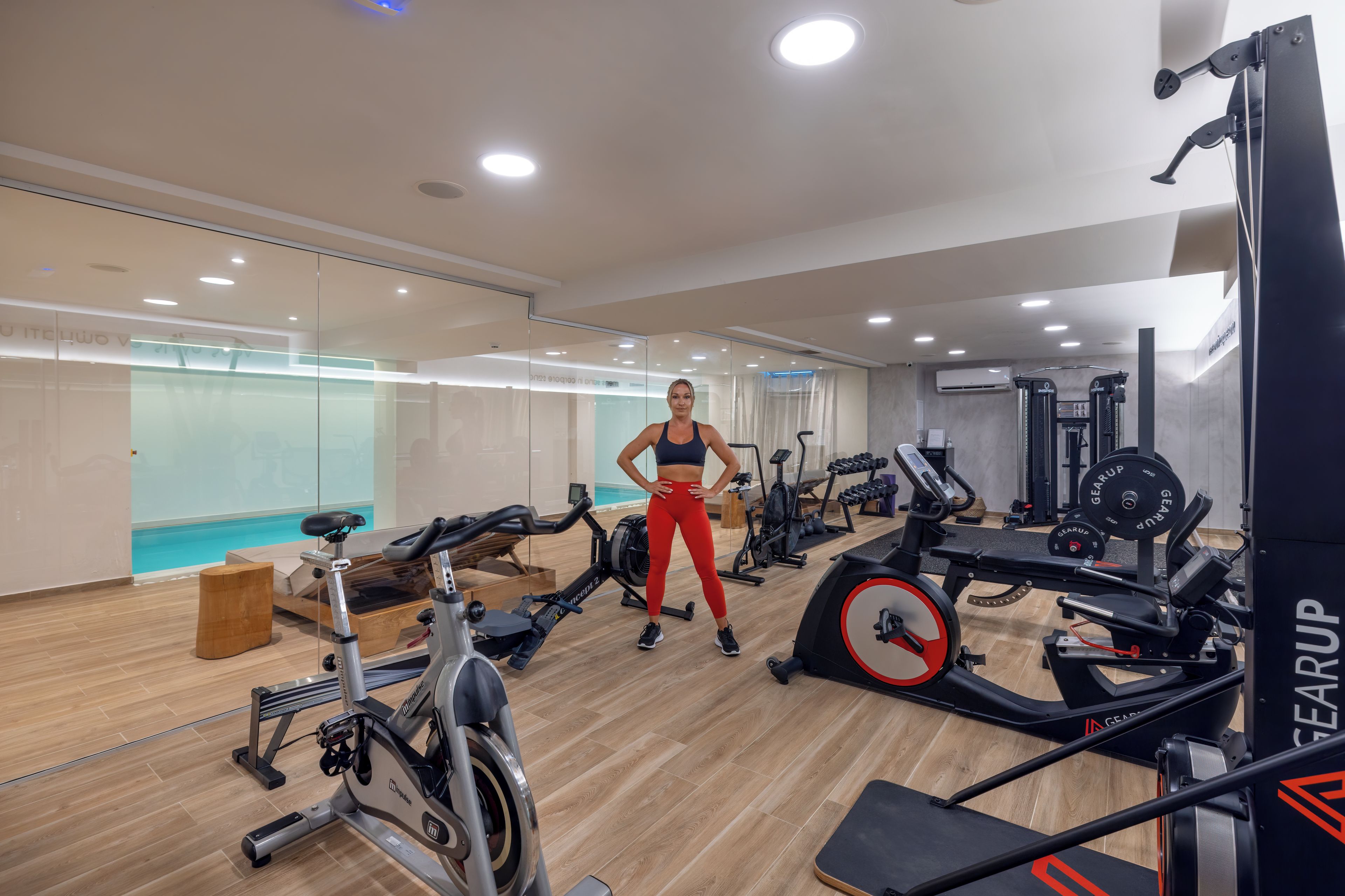 A gym with cardio machines, weightlifting equipment, and a mirrored wall.