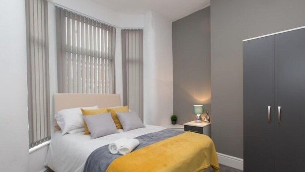 A modern bedroom with a bed, bedside table, lamp, and wardrobe. - Townhouse @166 Ruskin Rd (Crewe)