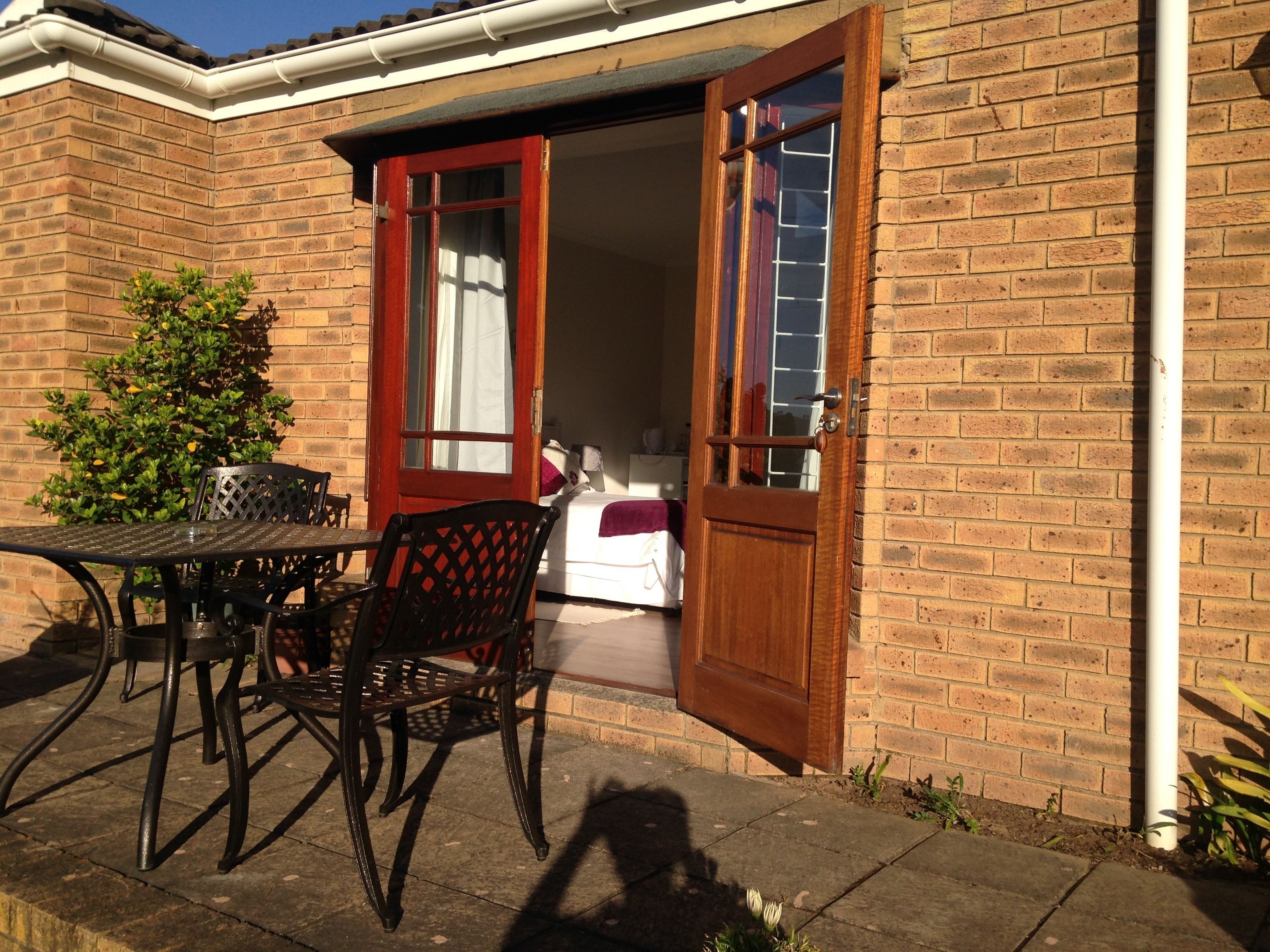 Un patio con una mesa y sillas, una puerta de madera y un muro de ladrillo.